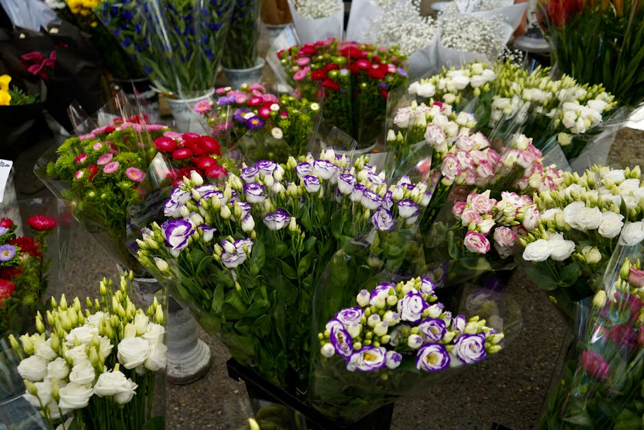A variety of freshly arranged floral bouquets displayed on a dark countertop, including purple and white eustoma (lisianthus) with delicate petals, clusters of small pink and white daisy-like flowers,